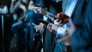 Menschen in Anzügen nutzen ihre Smartphones bei einer Konferenz oder einem öffentlichen Vortrag.