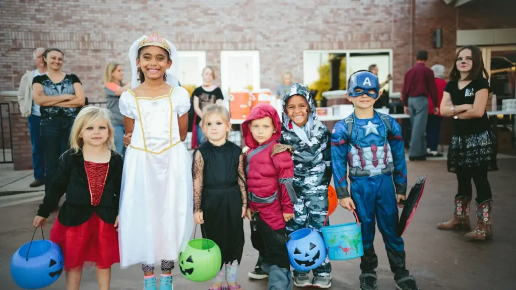 Eine Gruppe fröhlicher Kinder in Halloween-Kostümen sammelt Süßigkeiten bei einem abendlichen Rundgang.