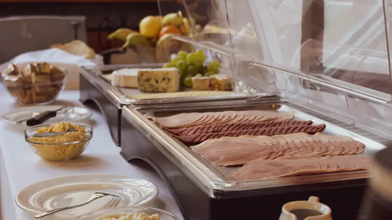 Ein reichhaltiges Frühstücksbuffet mit verschiedenen Aufschnitten, Käse und Obst in einem Hotel.