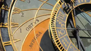 Detailaufnahme einer historischen astronomischen Uhr mit goldenen Sternzeichen und römischen Ziffern.