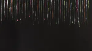 Bunte, vertikale Pinselstriche in verschiedenen Farben auf einem einfarbigen schwarzen Hintergrund.
